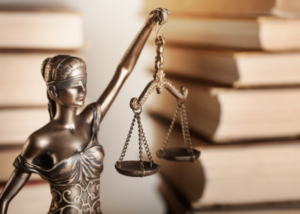 Imagem decorativa com a estátua da justiça e livros de fundo