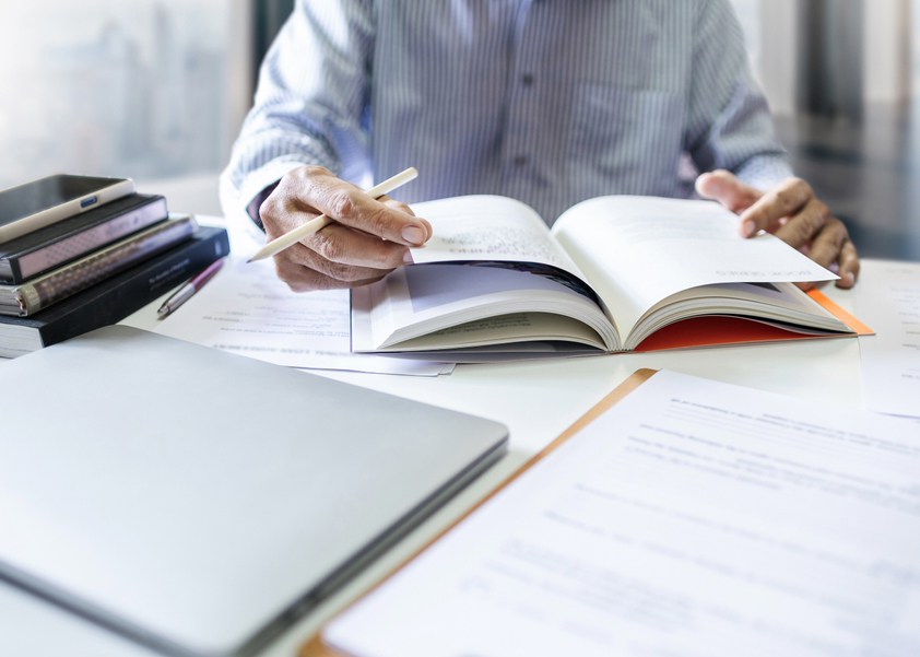 Businessman, lawyer, legal advisor, working with laptop and reading legal processing books for accuracy in contract documents reviewing business contracts before giving advice to customers